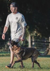 Man walking Belgian Malinois during outdoor dog training